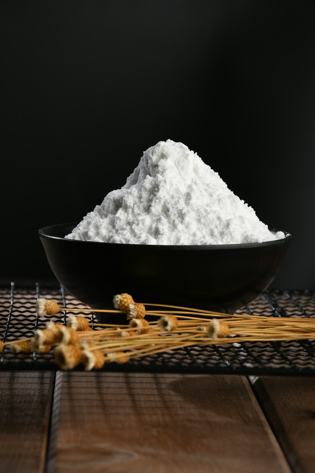 White flour powder on black plate with wheat stalks